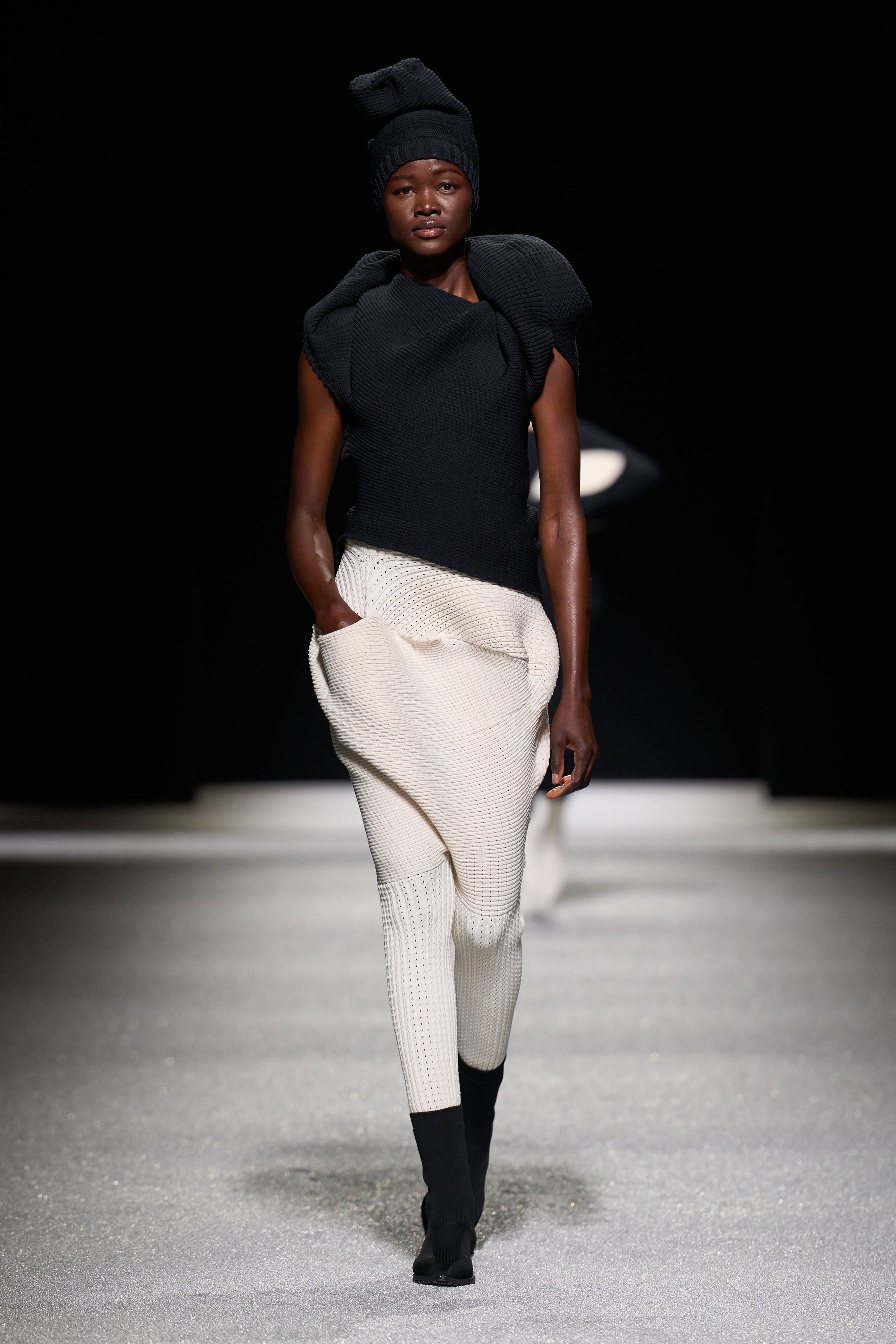 Issey Miyake 这一季把“留白”做成了真正可被看见的力量：黑白灰的大面积静默、宽松针织与褶皱结构先建立禅意秩序，随后以明黄、亮粉与雕塑化体量突然打破沉静，让衣服像在呼吸，也像在生长。它不是简单的极简主义，而是一种把工艺、身体与空间关系重新推向前台的诗性实验-顽石频道趋势研究